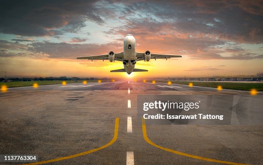 Airplane taking off from the airport runway in beautiful sunset light Airplane taking off from the airport runway in beautiful sunset light