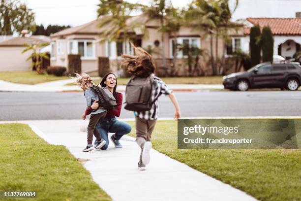kids running to her mother after school - kids bus stop stock pictures, royalty-free photos & images