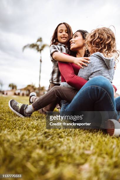 mutter umarmt die söhne in einem öffentlichen park - tiny mexican girl stock-fotos und bilder