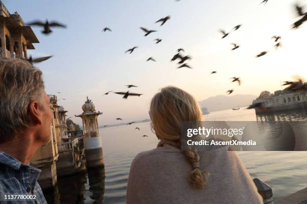 couple look out to floating palace on lake at sunset - daily life in india stock pictures, royalty-free photos & images