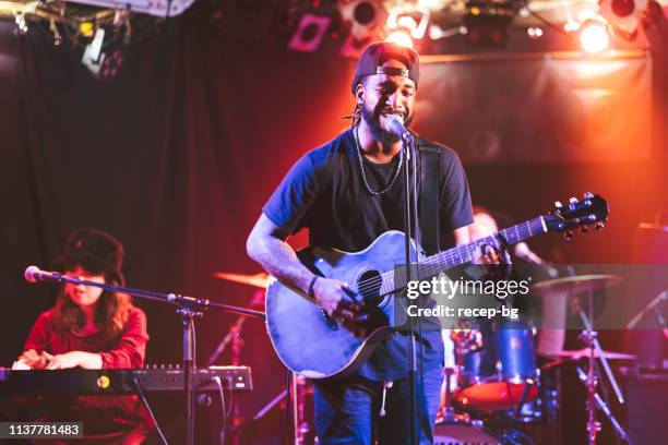 black male guitarist singing and playing acoustic guitar on stage - palco imagens e fotografias de stock