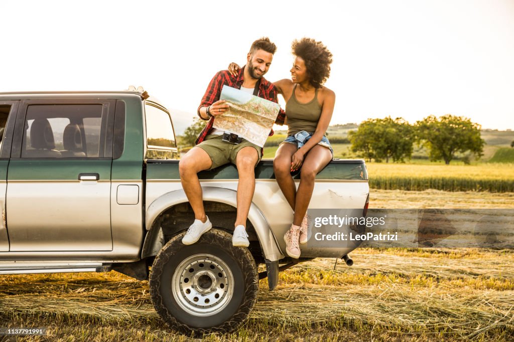 Young couple sitting in the car reading a road map