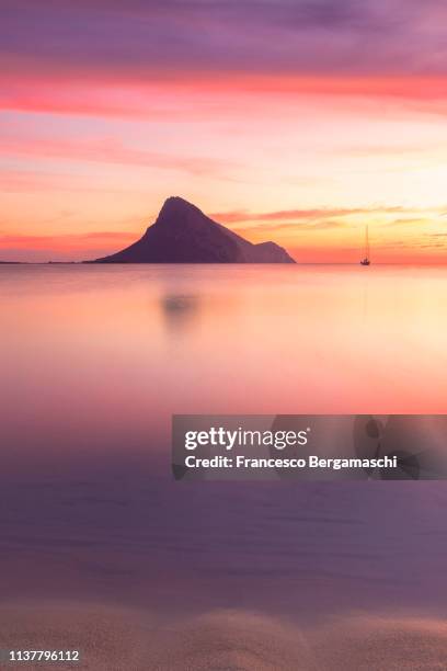 amazing sunrise on the beach of porto taverna with the tavolara island in the background. loiri porto san paolo, olbia tempio province, sardinia, italy, europe. - italian island photos et images de collection