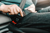 Close up of senior man fastening seat belt while sitting in his car.