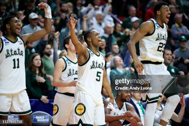 Aaron Henry, Cassius Winston and Xavier Tillman of the Michigan State Spartans celebrate from the bench against the Minnesota Golden Gophers during...