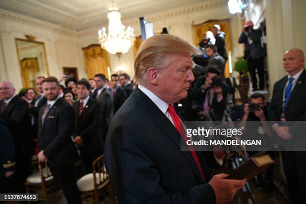 President Donald Trump departs with a trophy after speaking at an event honoring the Wounded Warrior Project Soldier Ride in the East Room of the...