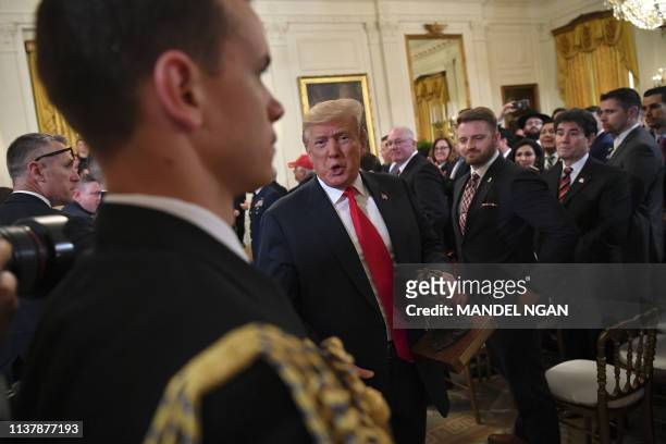 President Donald Trump departs with a trophy after speaking at an event honoring the Wounded Warrior Project Soldier Ride in the East Room of the...