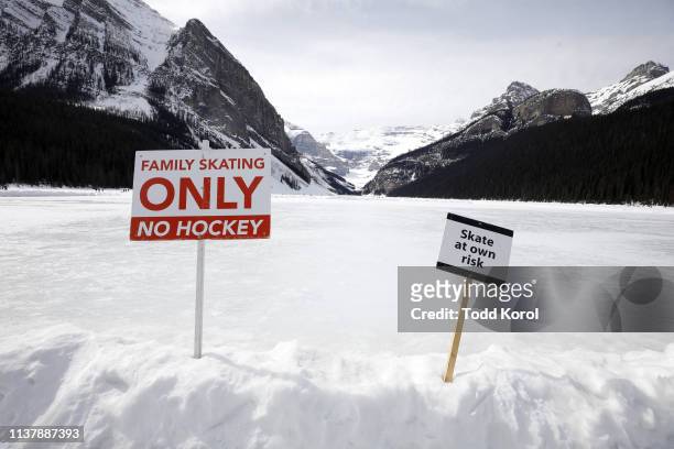 Climate Change Story: View of signs in snow reading FAMILY SKATING ONLY - NO HOCKEY and SKATE AT OWN RISK at Lake Louise. Winter sports in the parts...