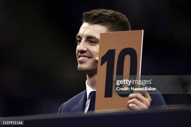 Max Whitlock shows a 10 score card as he sits on the judges panel during the Superstars of Gymnastics at The O2 Arena on March 23, 2019 in London,...