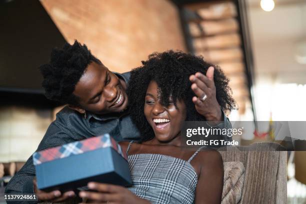 husband making a surprise giving a present to his wife at home - exchanging gifts stock pictures, royalty-free photos & images