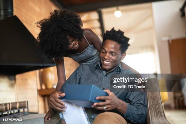 vrouw het maken van een verrassing het geven van een cadeautje aan haar man thuis - boyfriend stockfoto's en -beelden