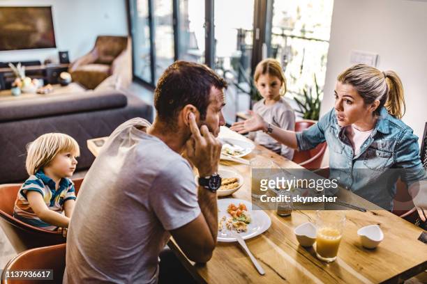 jonge ouders ruzie terwijl ze lunchen met hun kinderen thuis. - argument stockfoto's en -beelden
