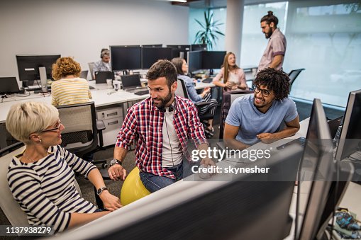 Happy Computer Programmers Talking While Working In The Office High-Res ...