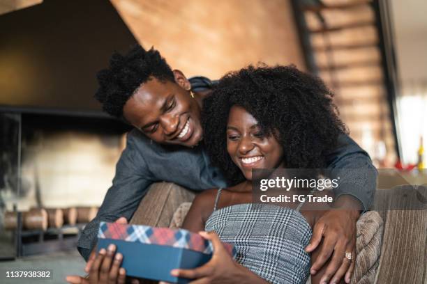 husband making a surprise giving a present to his wife at home - exchanging gifts stock pictures, royalty-free photos & images