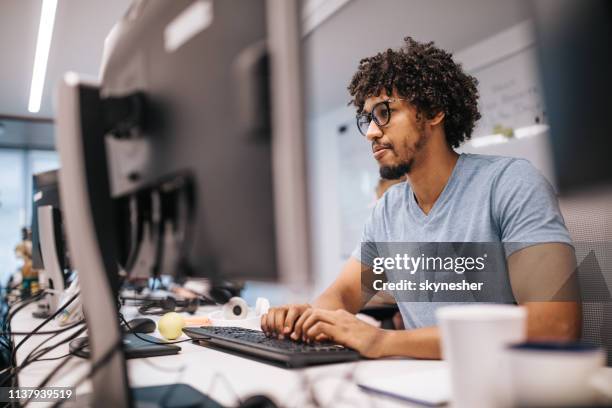 jonge afro-amerikaanse programmeur werkt op desktop pc in het kantoor. - graphic designer stockfoto's en -beelden