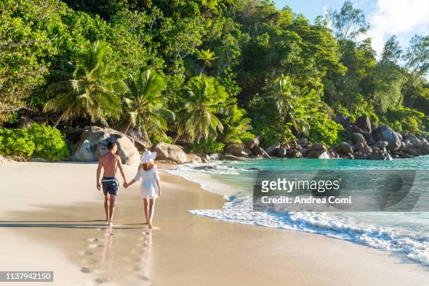 a couple walking through a tropical beach - seychelles stock pictures, royalty-free photos & images