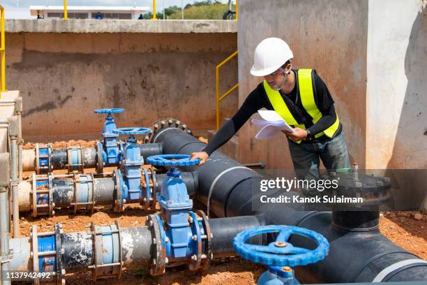 worker adjusting gauge at oil refinery - valvola di sfiato foto e immagini stock