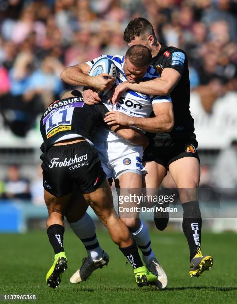 Jamie Roberts of Bath Rugby is tackled by Olly Woodburn and Ollie Devoto of Exeter Chiefs during the Gallagher Premiership Rugby match between Exeter...
