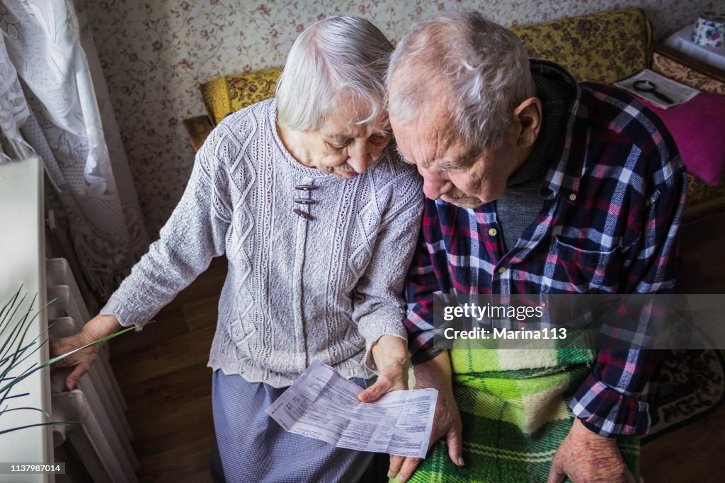 Mujer sosteniendo efectivo delante del radiador calefactor. Pago por calentamiento en invierno. Enfoque selectivo.
