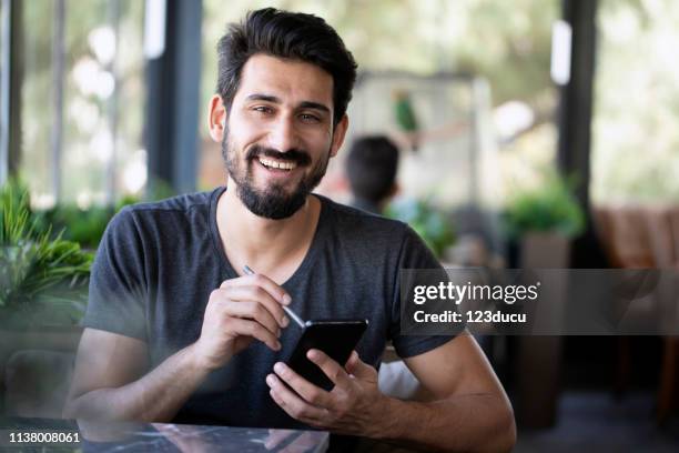 indian man bij cafe - young muslim man stockfoto's en -beelden