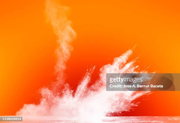 explosion by an impact of a cloud of particles of powder and smoke of color white on a orange background. - orange colour background stock pictures, royalty-free photos & images