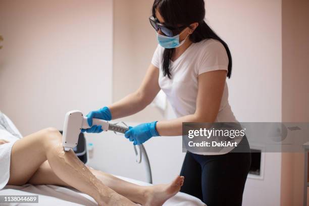 beautician removing hair with laser epilator - wax strip stock pictures, royalty-free photos & images