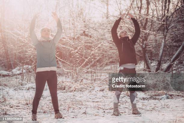 frauen üben winter-yoga in der natur - man standing in the snow stock-fotos und bilder