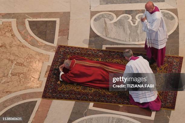 Papal Master of Ceremonies, Monsignor Guido Marini arranges Pope Francis' cloth as the Pope prays during the Celebration of the Lord's Passion on...