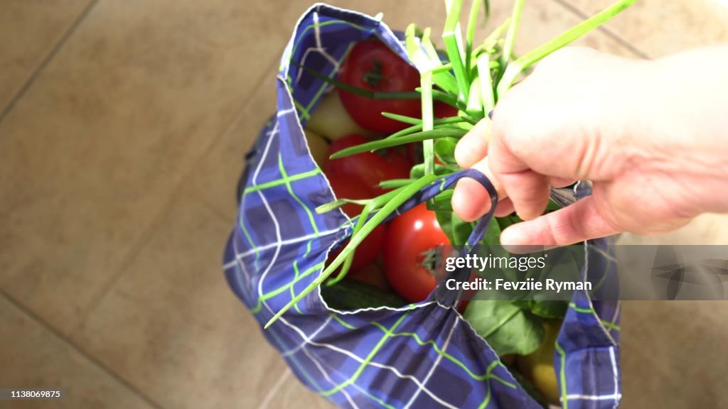 Zero waste lifestyle. Eco Shopping. Young man holding canvas produce bag with fruits and vegetables