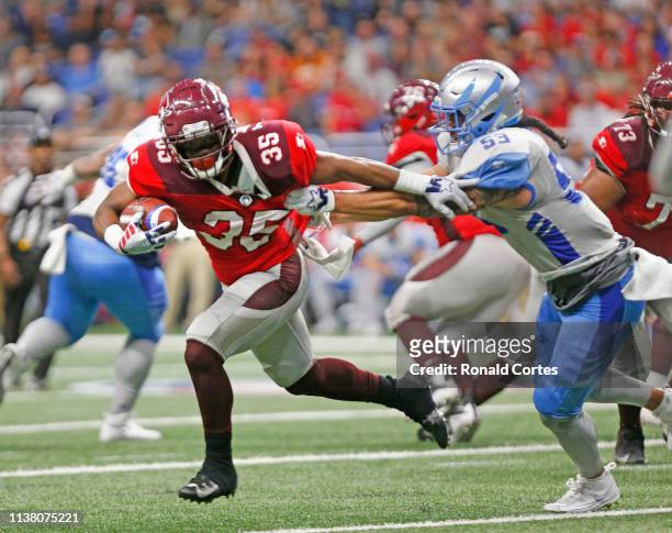 Trey Williams of the San Antonio Commanders tries to avoid the tackle of John Timu of the Salt Lake Stallions at Alamodome on March 23, 2019 in San...