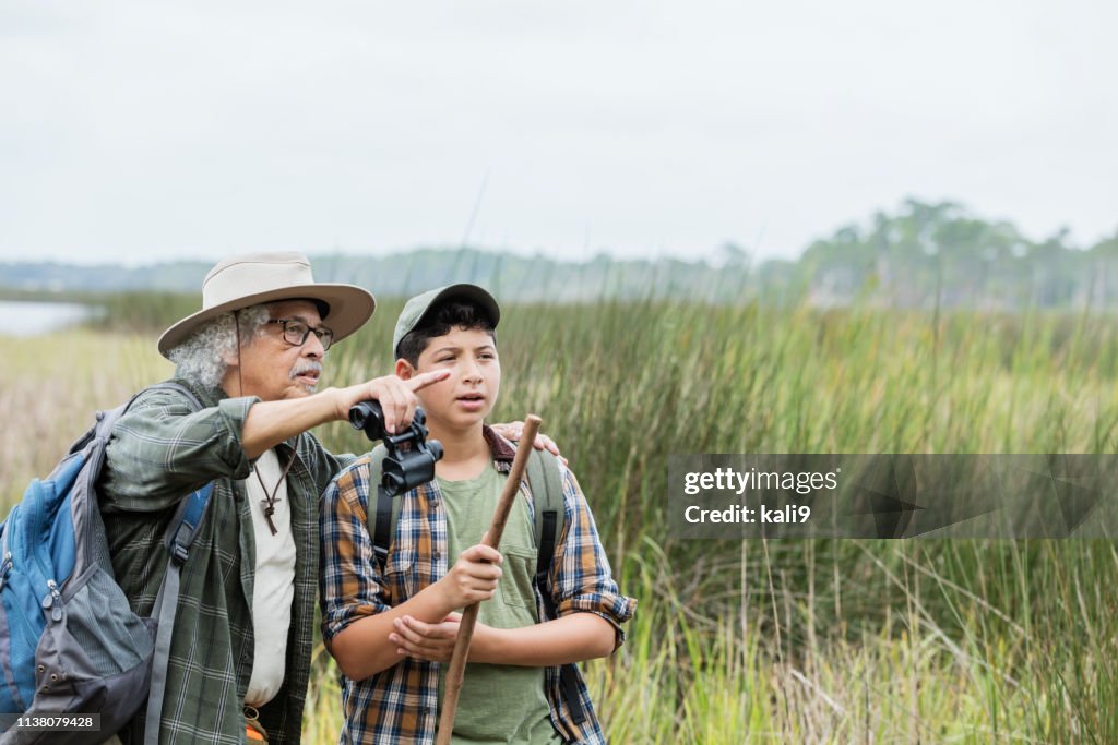 Niño hispano senderismo con abuelo, observación de aves