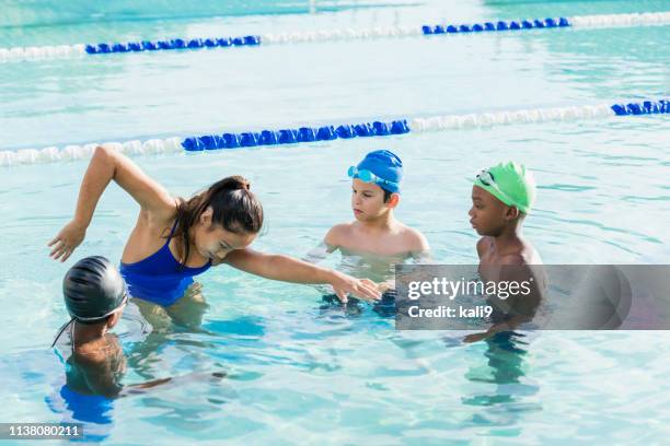 giovane donna che dà lezioni di nuoto a gruppi multietnici - nuoto foto e immagini stock