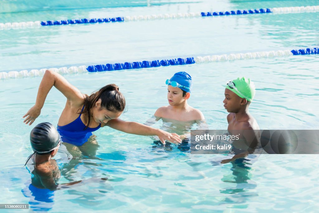 Young woman giving swim lessons to multi-ethnic group