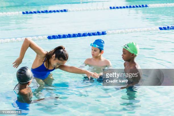 young woman giving swim lessons to multi-ethnic group - swimming stock pictures, royalty-free photos & images