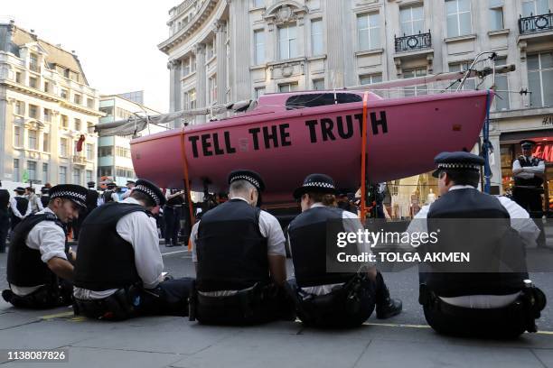 Police officers surround the pink boat which climate change activists used as a central point of their encampment as they occupied the road junction...