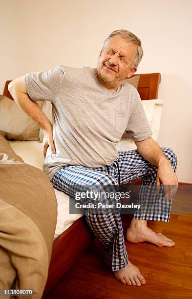 mature man with back pain - back pain bed stock pictures, royalty-free photos & images