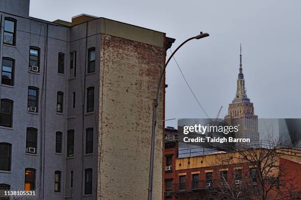 empire state building and tenament buildings in new york city - new york city wall stock pictures, royalty-free photos & images