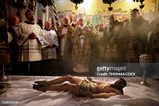 Franciscan friars pray over the statue of Jesus lying down on the Anointing Stone during a reenactment of the Funeral of Jesus inside the Church of...