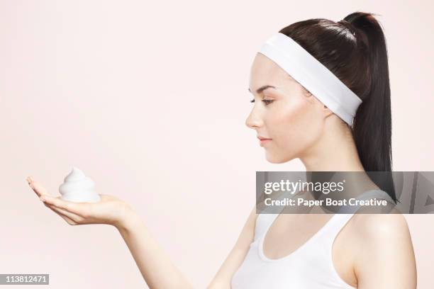 young woman holding washing foam in her hands - mousse para cabelos imagens e fotografias de stock