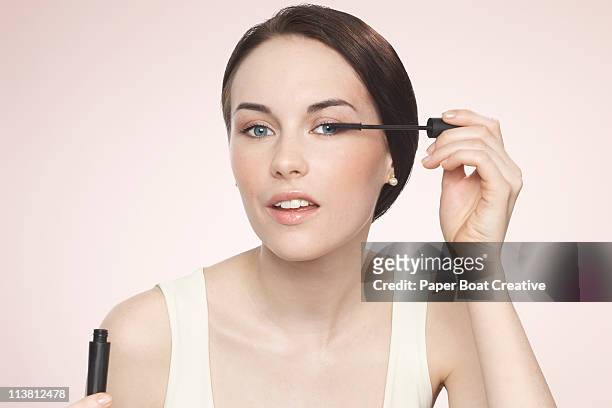 young woman applying black mascara - woman mascara stock pictures, royalty-free photos & images