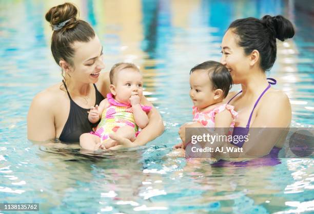 raising their little ones with an important life skill - mother and baby taking a bath stock pictures, royalty-free photos & images