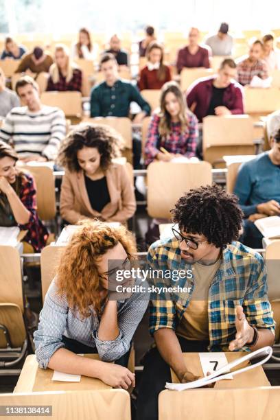 studenten, die bei der lektüre eines vortrags über eine klasse zusammenarbeiten. - university student stock-fotos und bilder