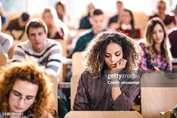 young university student feeling bored on a class at lecture hall. - attending college stock pictures, royalty-free photos & images