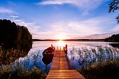 Wooden pier with fishing boat at sunset on a lake in Finland