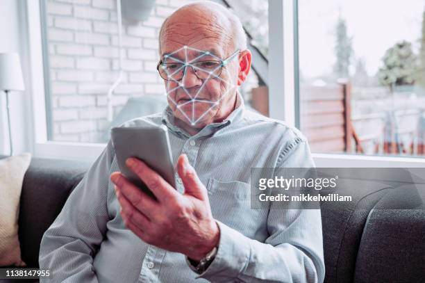 facial recognition software scans the face of senior man holding smart phone - sensor technology stock pictures, royalty-free photos & images