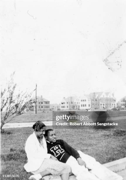 Student, wearing a sweater from Hampton Institute , relaxes on the grounds with a lady friend, Hampton, VA, early twentieth century.