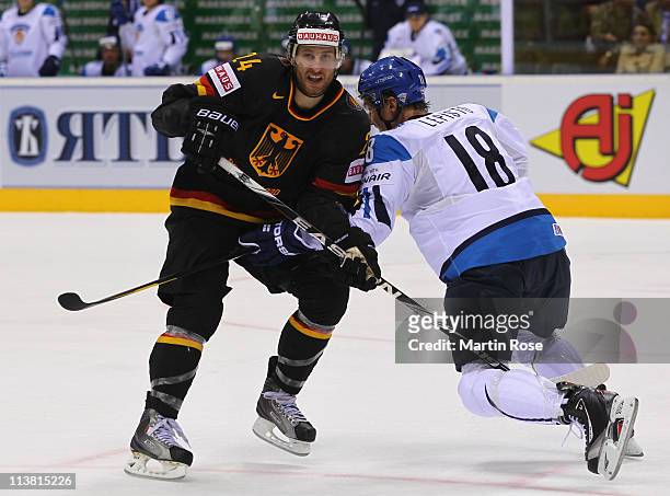 Andre Rankel of Germany skates against Sami Lepisto of Finland battle for the puck during the IIHF World Championship qualification match between...