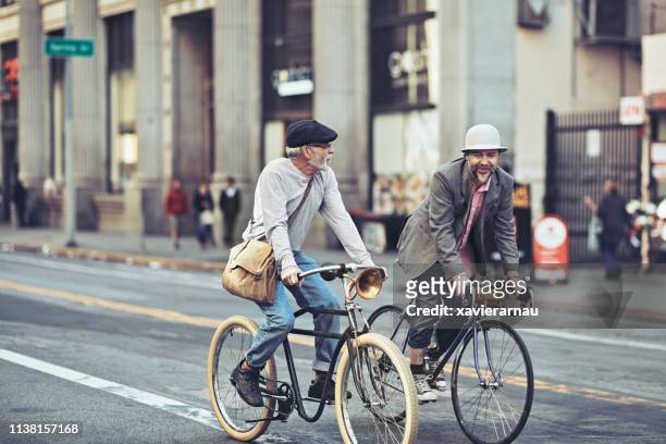 friends talking while cycling on city street - a la moda stock pictures, royalty-free photos & images