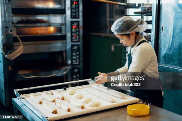 ミッドアダルト女性は、工業用キッチンでパン��を焼く - 郷土料理　日本 ストックフォトと画像