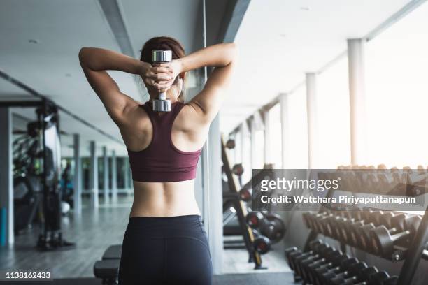 fitness asian girl lifting dumbbell at gym. - mancuerna fotografías e imágenes de stock